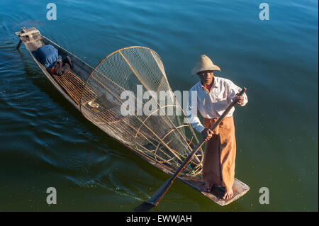 Burmese fisherman on bamboo boat catching fish in traditional way with handmade net. Inle lake, Myanmar (Burma) travel  destinat Stock Photo