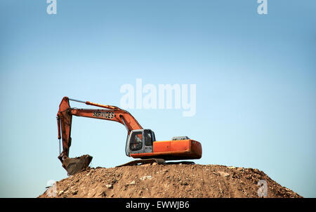 Backhoe on mound of dirt Stock Photo