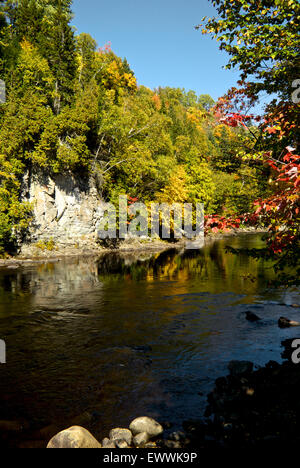 Trees in spectacular early autumn colours reflected in river parc Canyon Sainte Anne Quebec