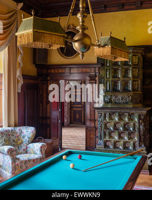 Billiard table in room with tiled stove and chintz upholstered armchair Stock Photo