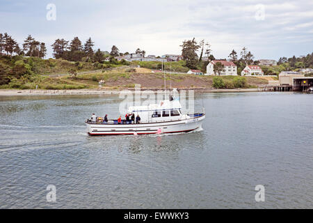 A salmon fishing boat heads into Newport, Oregon harbor after a day of fishing in the Pacific Ocean Stock Photo