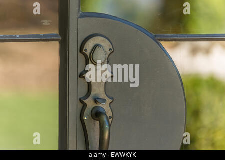 Black Venetian bronze handle in glass pane door Stock Photo
