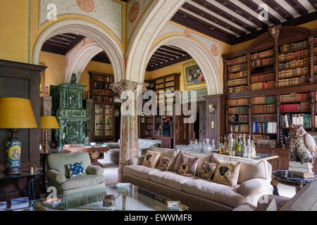 Stately drawing room with large bookcase, structural arches and green tiled stove Stock Photo