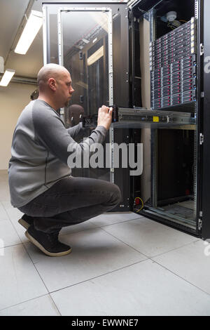 System administrator working on a network server in a server room Stock Photo