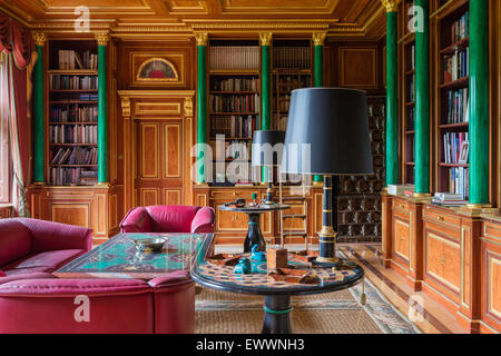 Pink leather armchairs and sofa in sitting room with inbuilt book cases, green coloumns and gilt coffered ceiling Stock Photo