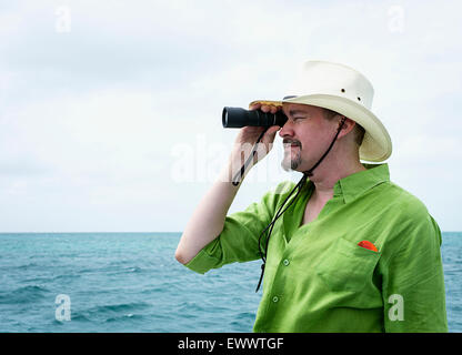 A man holding a monocular looking out to the ocean Stock Photo