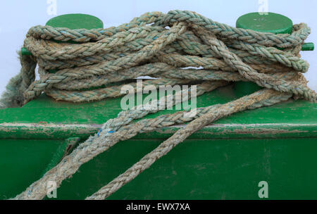 Tied mooring ropes on a green metal harbor bollard in the harbor of IJmuiden, North Holland, The Netherlands. Stock Photo