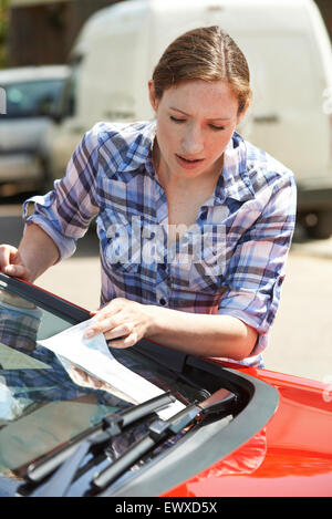 Frustrated Female Motorist Looking At Parking Ticket Stock Photo