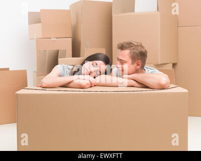 young caucasian couple resting on cardoard box after moving in house Stock Photo