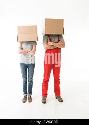 woman and man standing with hands crossed against their chests, hiding their heads under cardboard boxes. on white background Stock Photo