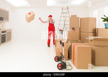 deliveryman unloading cardboard boxes into new house Stock Photo