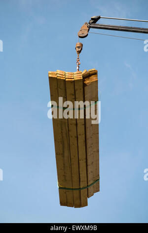 Timber / wood / planks / joist / joists being delivered by crane to a house roof top / new dorma extension. UK Stock Photo