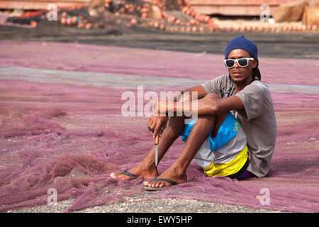 Creole fisherman mending fishing nets in the harbour of fishing village Palmeira on the island of Sal, Cape Verde / Cabo Verde Stock Photo