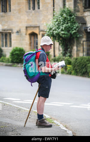 Hiker checking directions in Stanton village with honey coloured Cotswold limestone buildings in the background. There are no sh Stock Photo