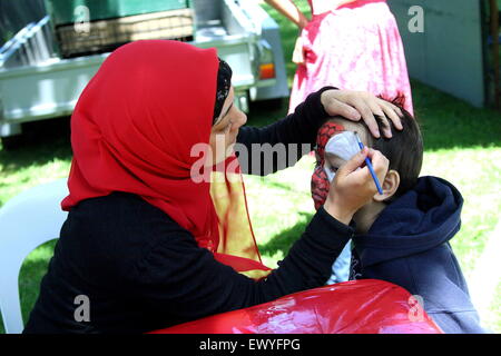 Muslim female face painter painting a child's face during Eid festival in Dandenong Melbourne Victoria Australia Stock Photo