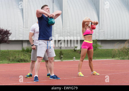 Group Of Young People Doing A Kettle Bell Exercise Outdoor With Instructor Stock Photo