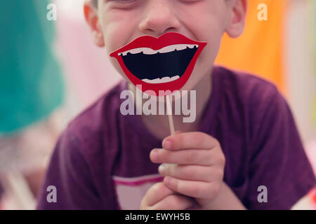 Boy holding a smile prop on a stick Stock Photo