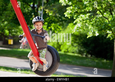 Boy sitting on a swing in the playground, Czech Republic Stock Photo