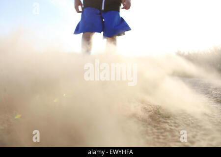 Low angle view of a boy in shorts with sand blowing Stock Photo