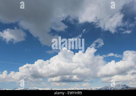 White cumulus clouds with a blue background sky. moving over the mountain tops Stock Photo