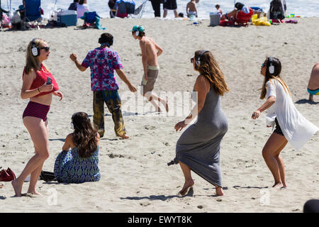 San Luis Obispo, California - young adults having fun and dancing on the beach wearing headphones in a hush concert, May 03 2015 Stock Photo