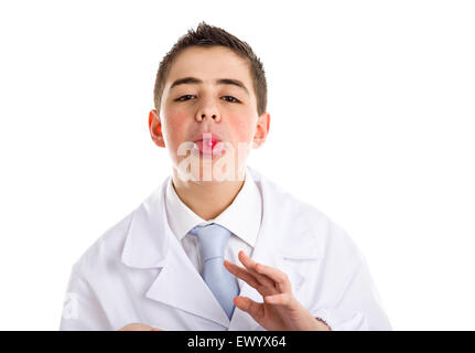 Boy dressed as a doctor in light blue tie and white coat helps to feel medicine more friendly: he is showing his tongue with a pill on it. His acne skin has not ben retouched Stock Photo