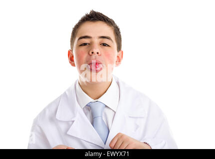 Boy dressed as a doctor in light blue tie and white coat helps to feel medicine more friendly: he is showing his tongue with a pill on it. His acne skin has not ben retouched Stock Photo