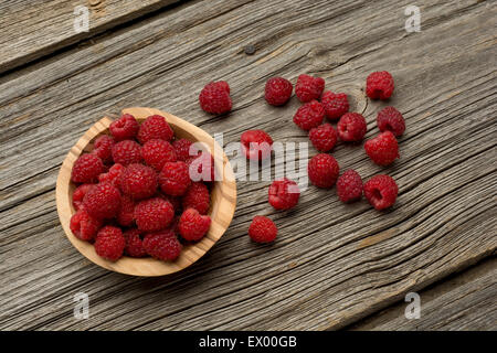 Raspberries in olive wood bowl on old wooden background Stock Photo