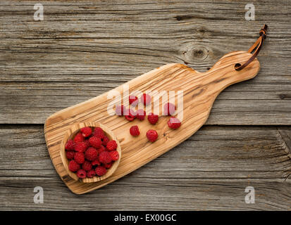 Raspberries in olive wood bowl on old wooden background Stock Photo