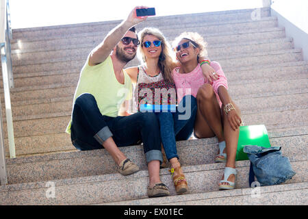 Portrait of three university students taking a selfie in the street. Stock Photo