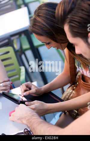 Portrait of couple of young students using a digital tablet in the bar. Stock Photo