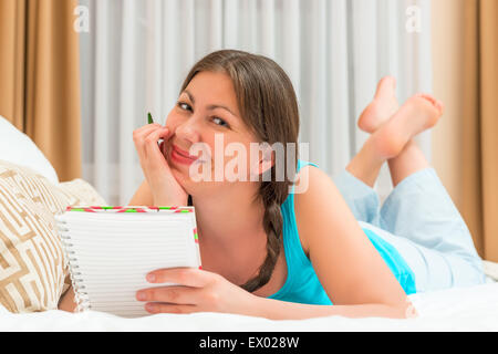 girl posing on a bed with notebook in hand Stock Photo