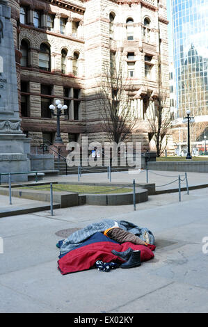 A homeless persons sleeps in front of Toronto's city hall Stock Photo