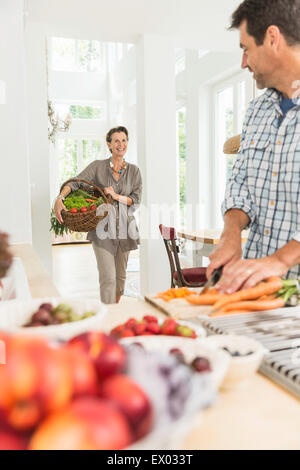 Couple carrying and preparing fresh vegetables in kitchen Stock Photo