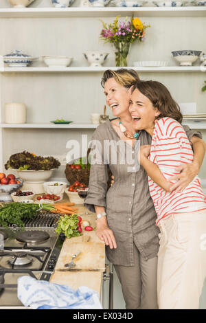 Senior woman hugging daughter in kitchen Stock Photo