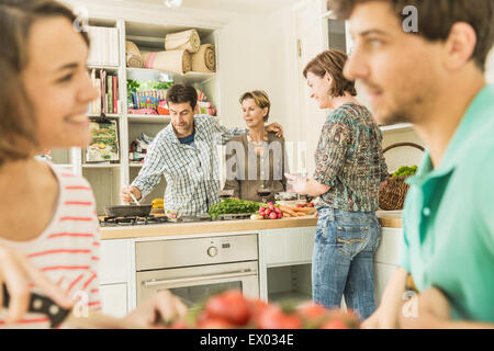 Five adult friends gathering for dinner party in kitchen Stock Photo