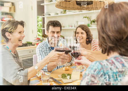 Adult friends making a toast with red wine at dining table Stock Photo