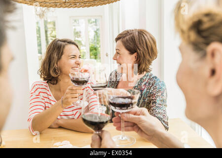 Four adult friends making a red wine toast at dinner Stock Photo