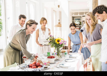 Family team laying out dining room table for party Stock Photo