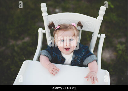 Portrait of baby girl in high chair Stock Photo