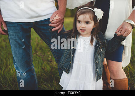 Young girl holding her parent's hands, low section