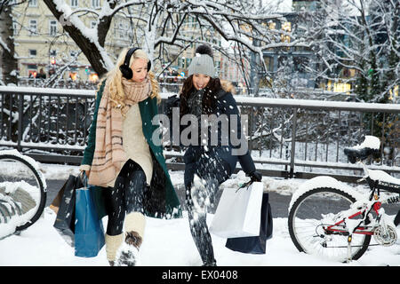 Two mid adult women in snow with shopping bags Stock Photo