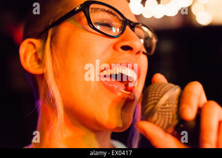 Punk girl singing into microphone, close-up Stock Photo