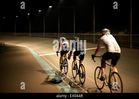 Cyclists cycling on track at velodrome, rear view