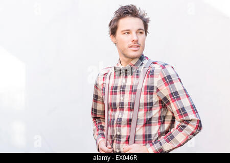 Young man standing in front of wall looking away Stock Photo