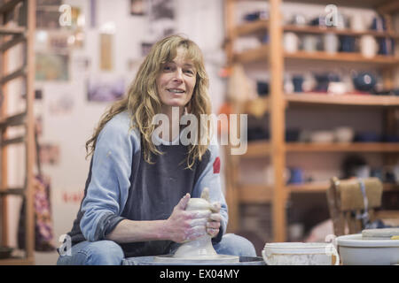 Portrait of female potter forming clay on pottery wheel Stock Photo