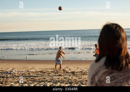 Group of friends playing on beach with ball Stock Photo