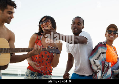 Group of friends singing and playing guitar on beach Stock Photo