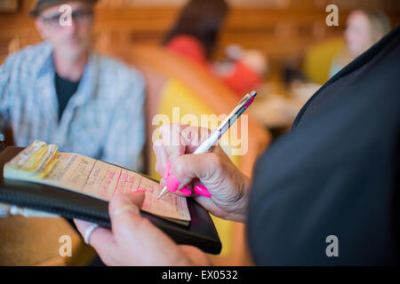 Cropped close up of waitress writing order on notepad in diner Stock Photo