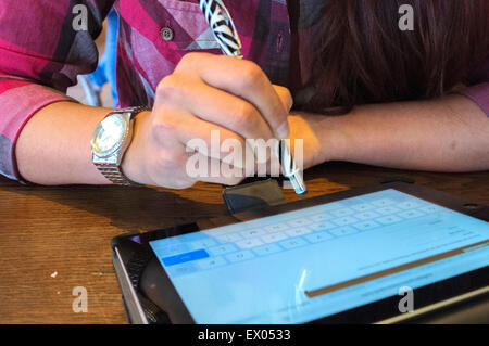 Cropped close up of young woman using pen to touchscreen digital tablet Stock Photo